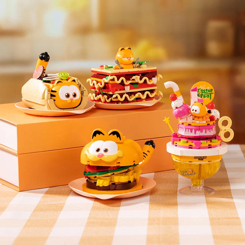 a collection of four figurines, each representing a different type of food, including a sandwich, cake, hot dog, and hot dog bun.