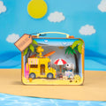 A toy suitcase containing a miniature beach scene with a yellow truck, a yellow surfboard, a yellow umbrella, and a yellow dog.