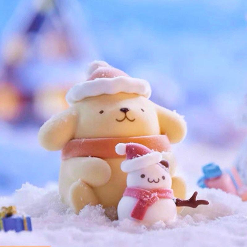 A yellow snowman and a small snowman figurine are sitting on a snowy surface, wearing winter hats and scarves.