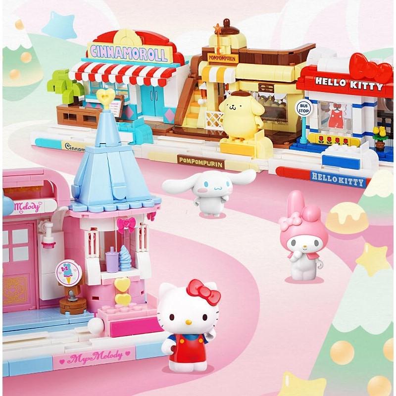 A collection of colorful Hello Kitty-themed playsets and figurines, including a pink and blue building, a yellow and brown building, and a pink and blue building with a red roof.