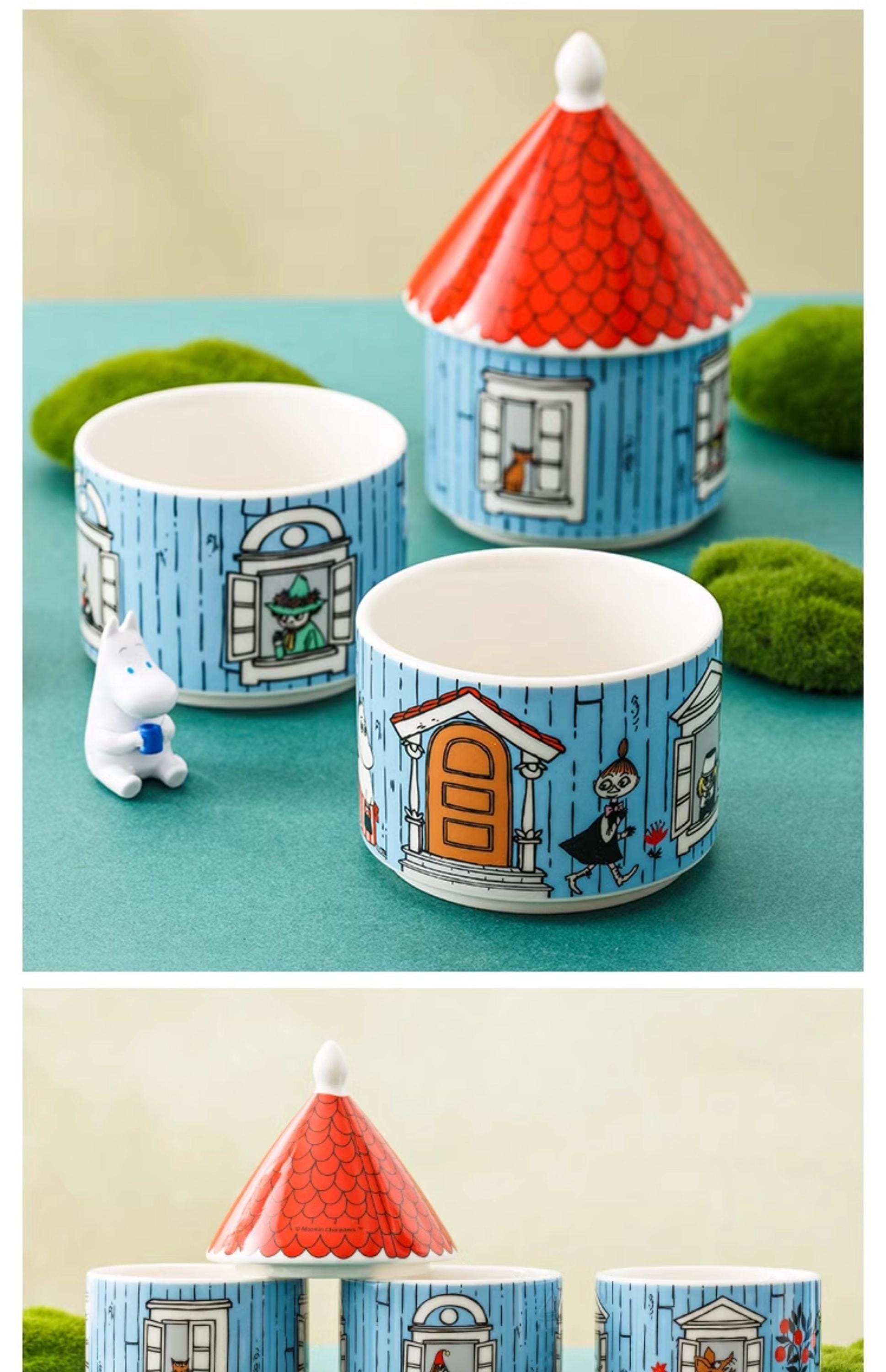 a collection of ceramic containers and figurines, including a small white unicorn figurine, a red and white ceramic house, and a blue and white ceramic cup.