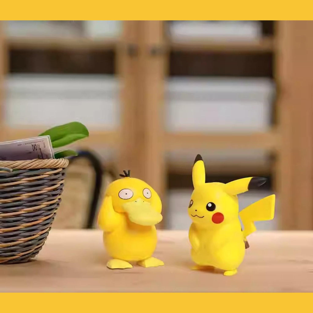 two Pokemon figurines, one of Pikachu and one of Quik-a-Pik, sitting on a table next to a basket.