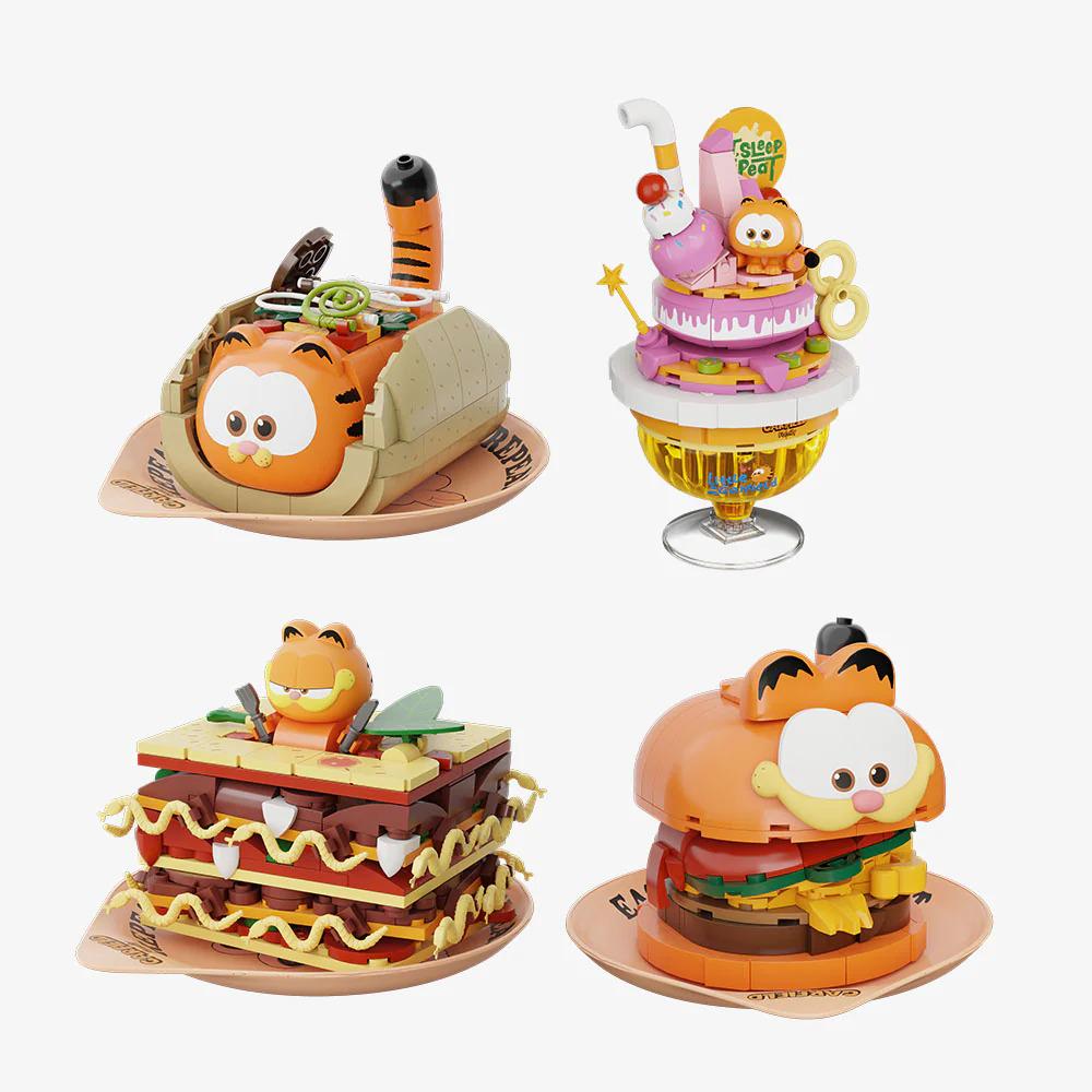 four different figurines or toy food items, each with unique designs and features. The figurines are arranged in a grid-like pattern, with each one placed on a separate plate. The figurines are designed to resemble various food items, such as sandwiches, cakes, and other desserts.