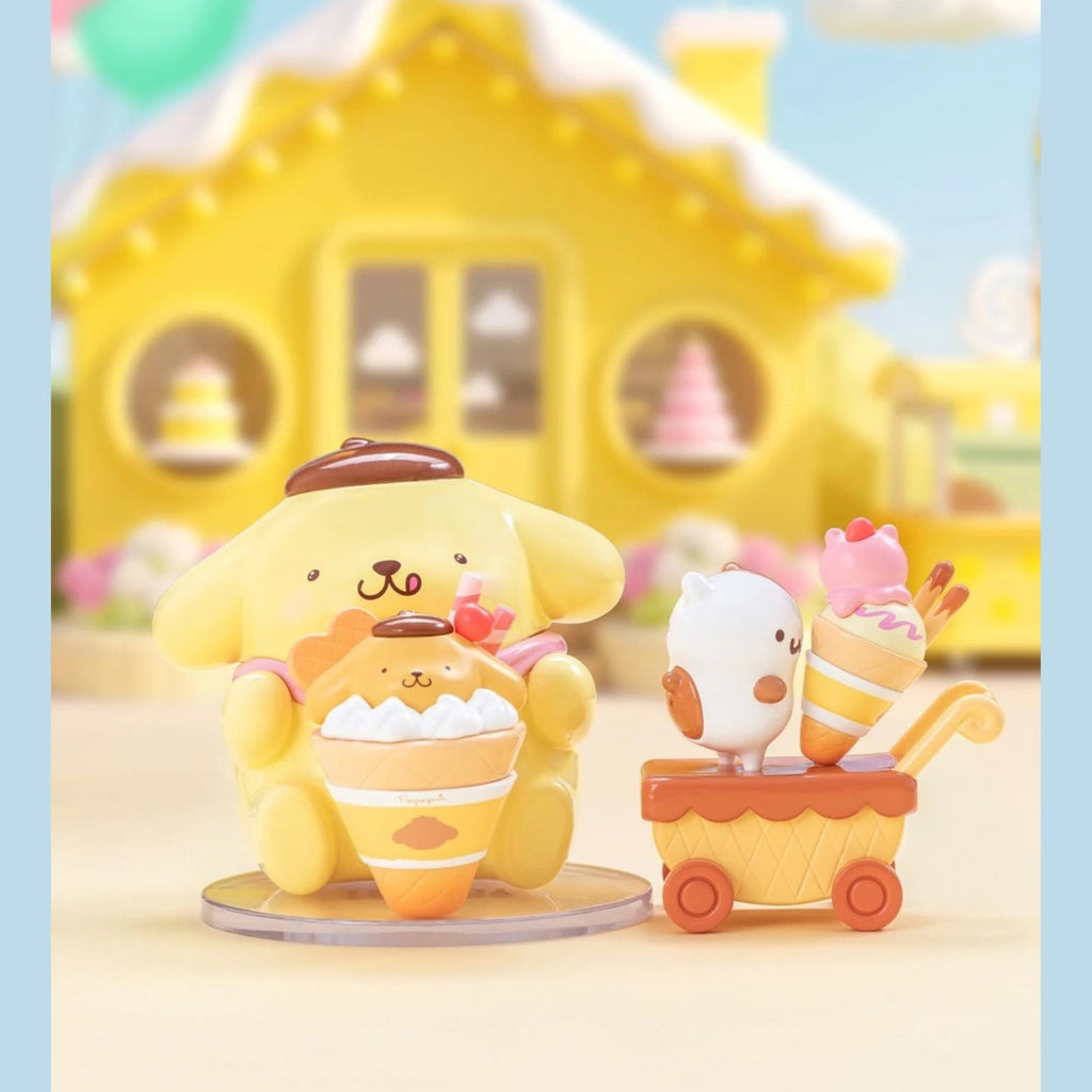 A yellow toy figurine is sitting on a table, holding a cupcake, with a small white figurine and a pink figurine on a cart behind it. In the background, there is a yellow house with a yellow roof and a pink tree.