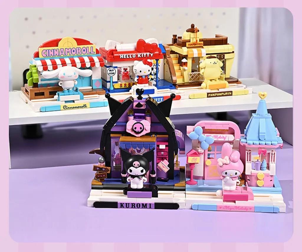 A collection of colorful Hello Kitty-themed playsets and figurines, including a pink and blue castle, a pink and purple pig, and a pink and blue bunny.
