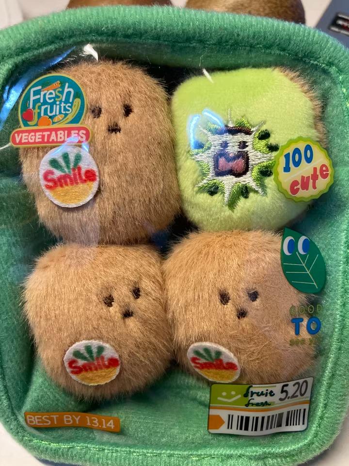 A package of four stuffed animal fruits, including kiwis and bananas, with various stickers and text on the packaging.