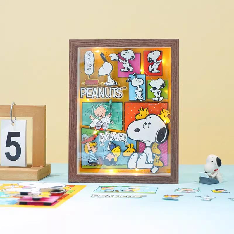 A framed collage of various Peanuts characters, including Snoopy, Woodstock, and other iconic figures, is displayed on a table.