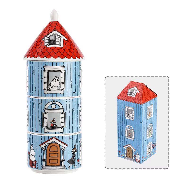 a ceramic tower-shaped container with a red roof and blue walls, decorated with illustrations of a house and a cat.