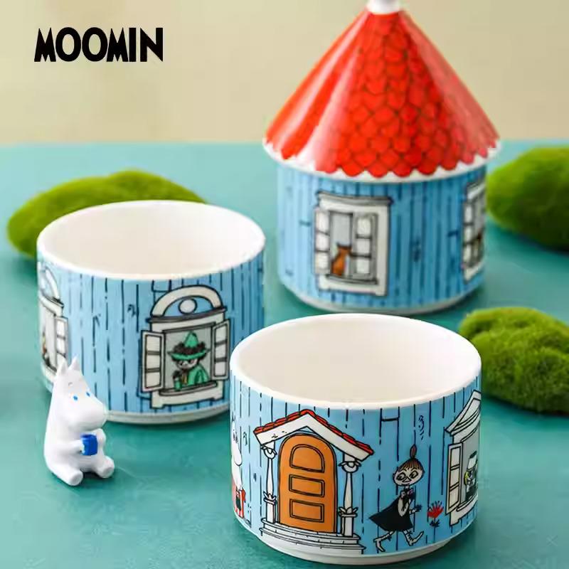 a collection of ceramic mugs and a small figurine, all with blue and white designs depicting a house and a character.