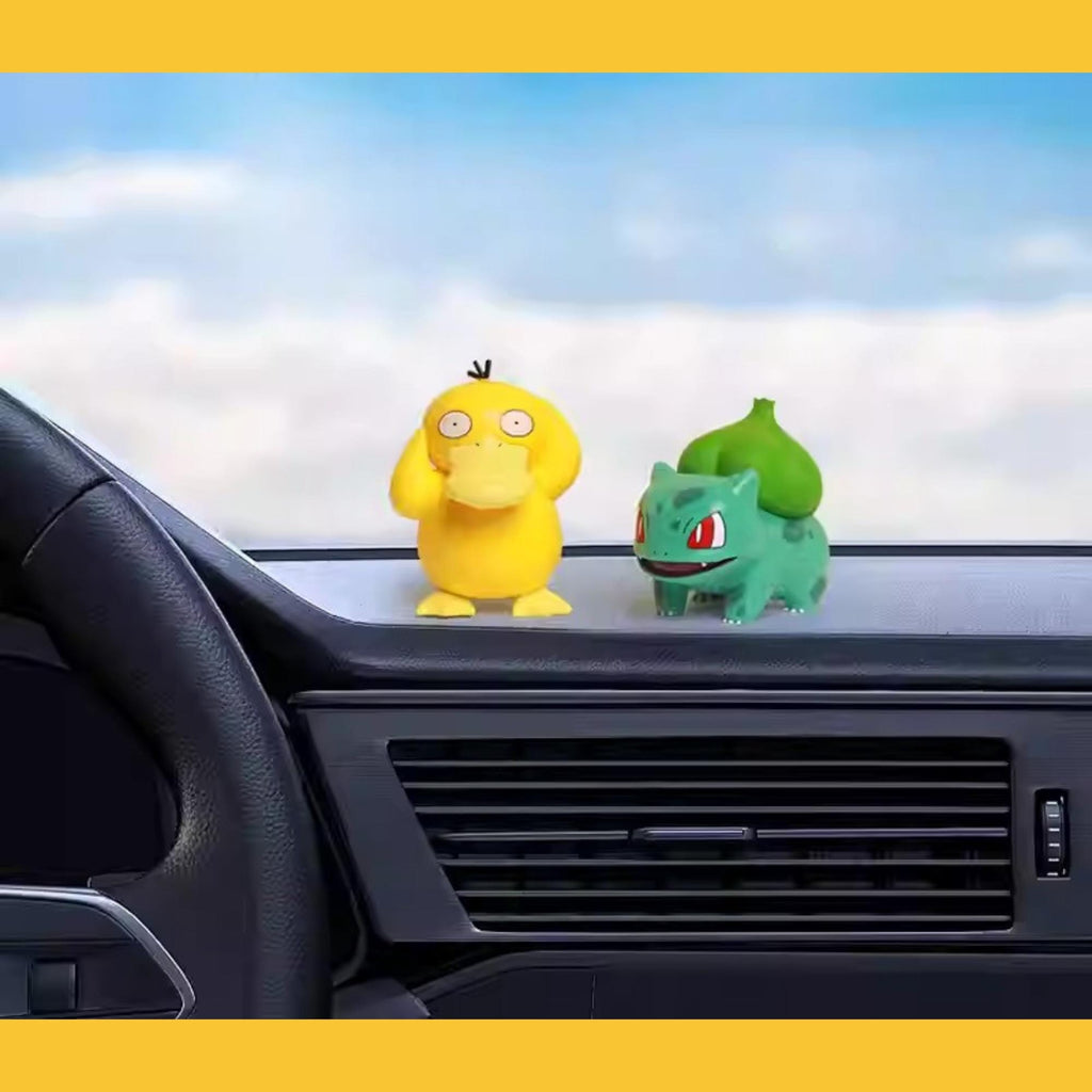 A yellow duck figurine and a green alien figurine are placed on the dashboard of a car, with a blue sky and clouds visible in the background.