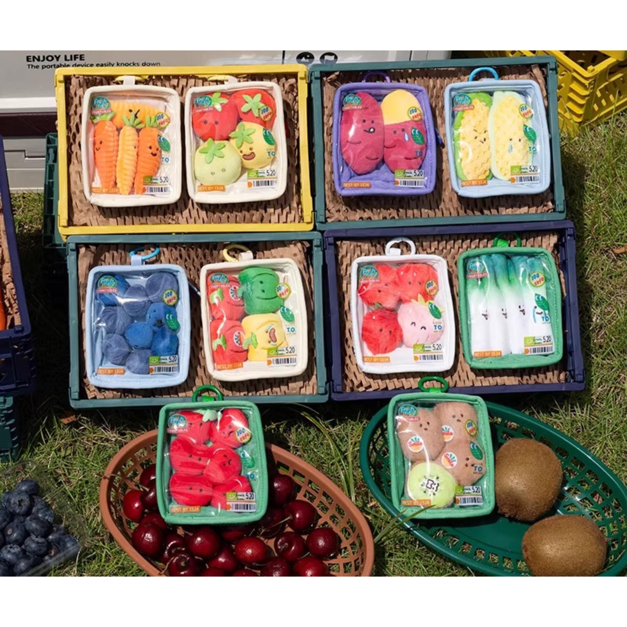 A collection of colorful plastic toy fruits and vegetables displayed in plastic containers on the grass.