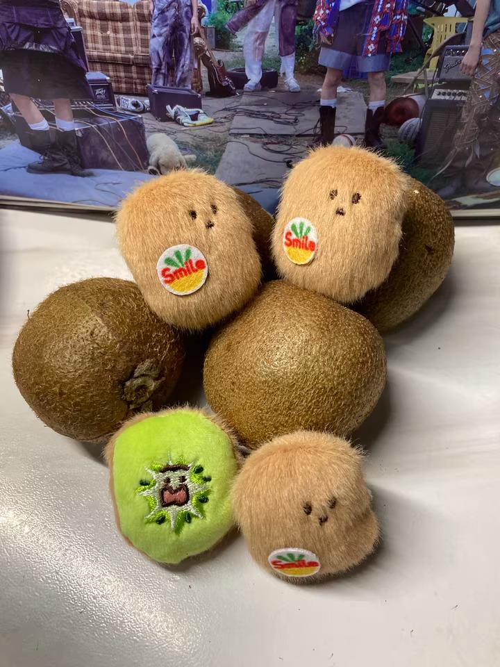 a collection of stuffed kiwi fruits with smiling faces, arranged on a surface.
