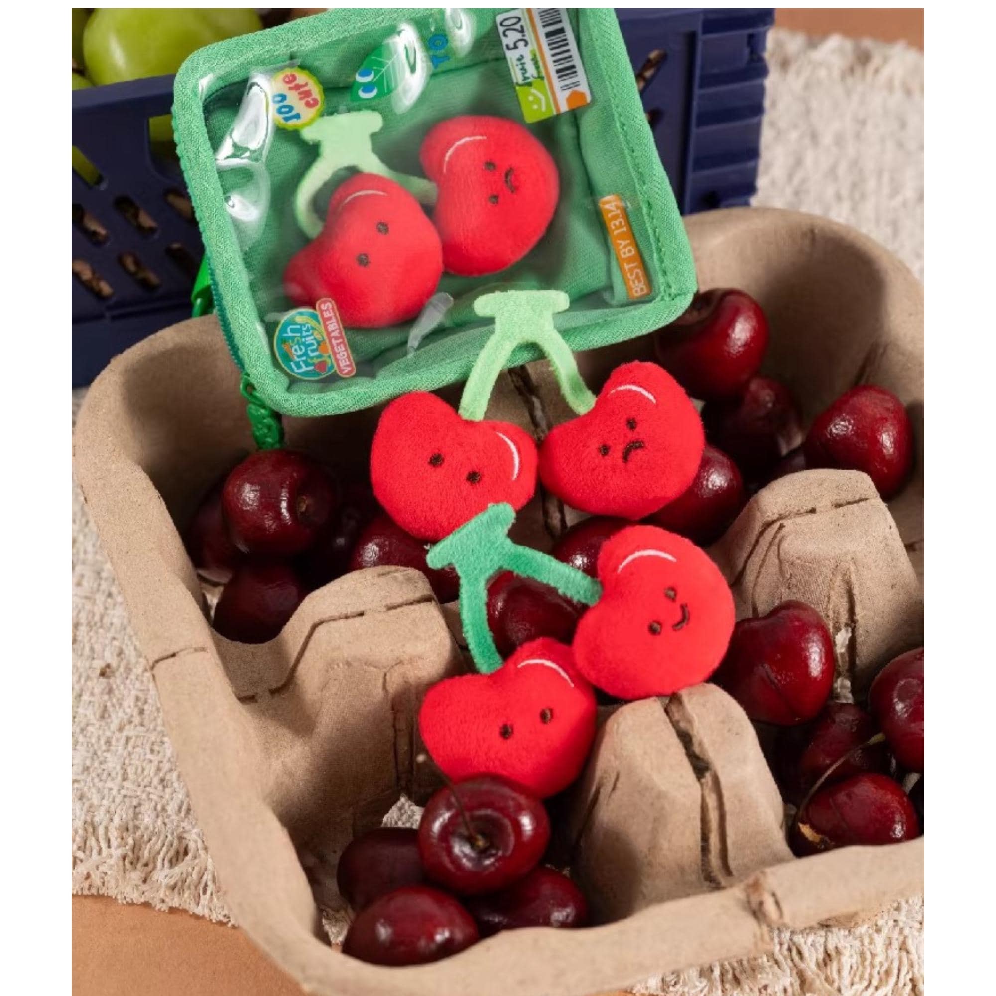 A cardboard box filled with red cherries, with a green plastic container containing red cherries placed on top of the box.