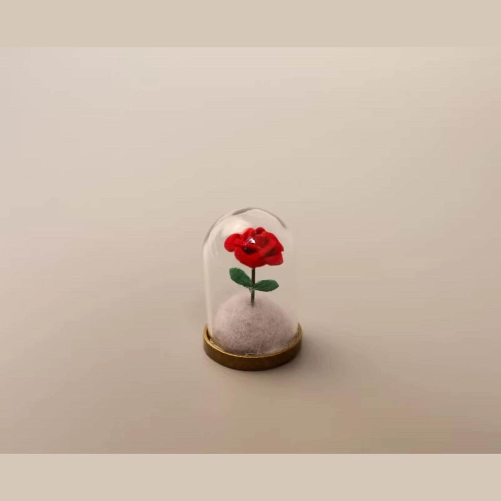 A small glass dome containing a red rose with a green stem.