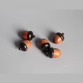 A group of five wooden acorns with black caps, arranged on a gray background.
