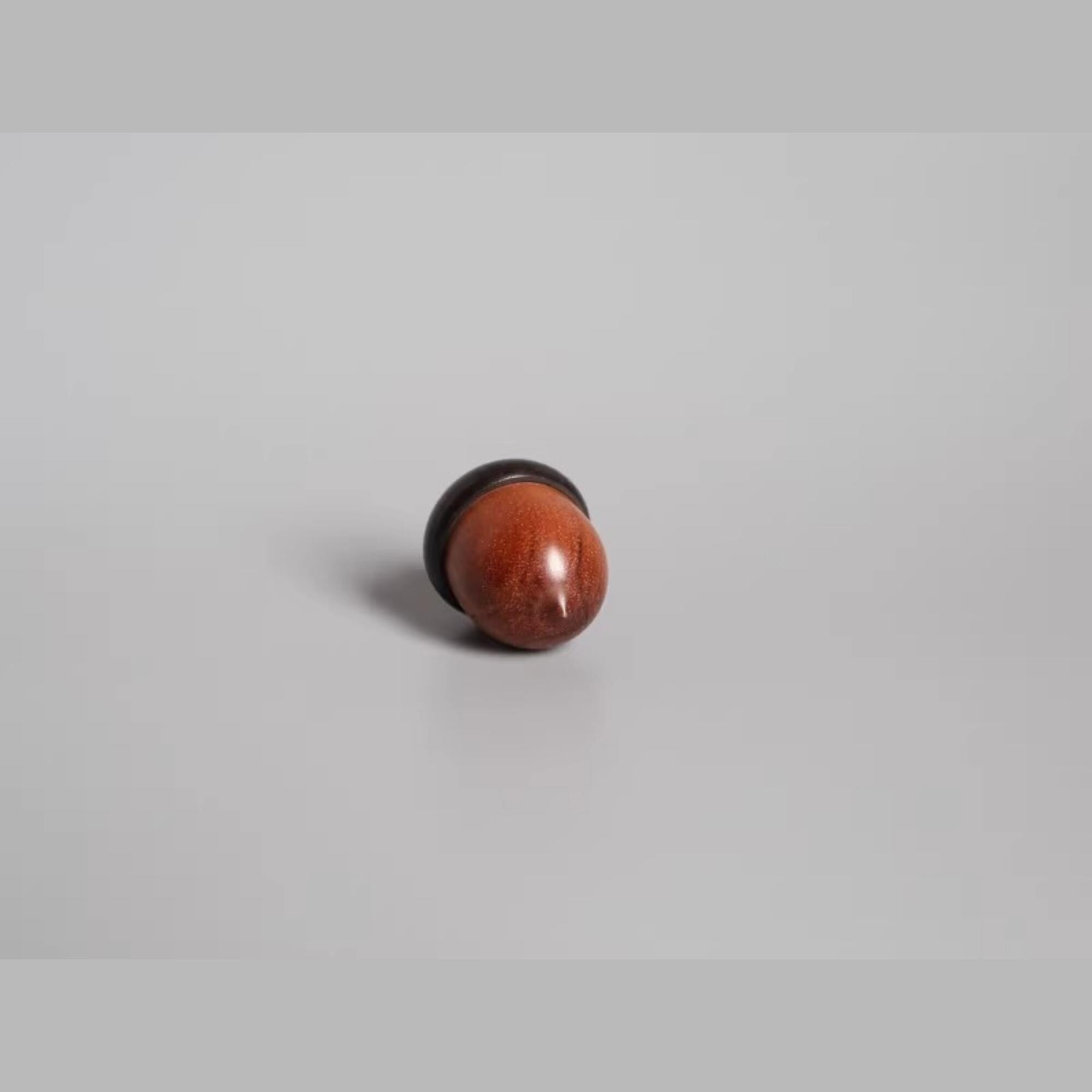 A single, round, brown object is centered against a plain, light gray background.