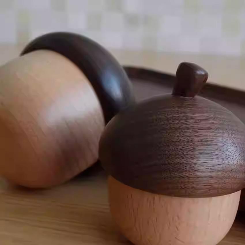two wooden objects with a textured finish, one with a dark finish and the other with a lighter finish, placed on a wooden surface.