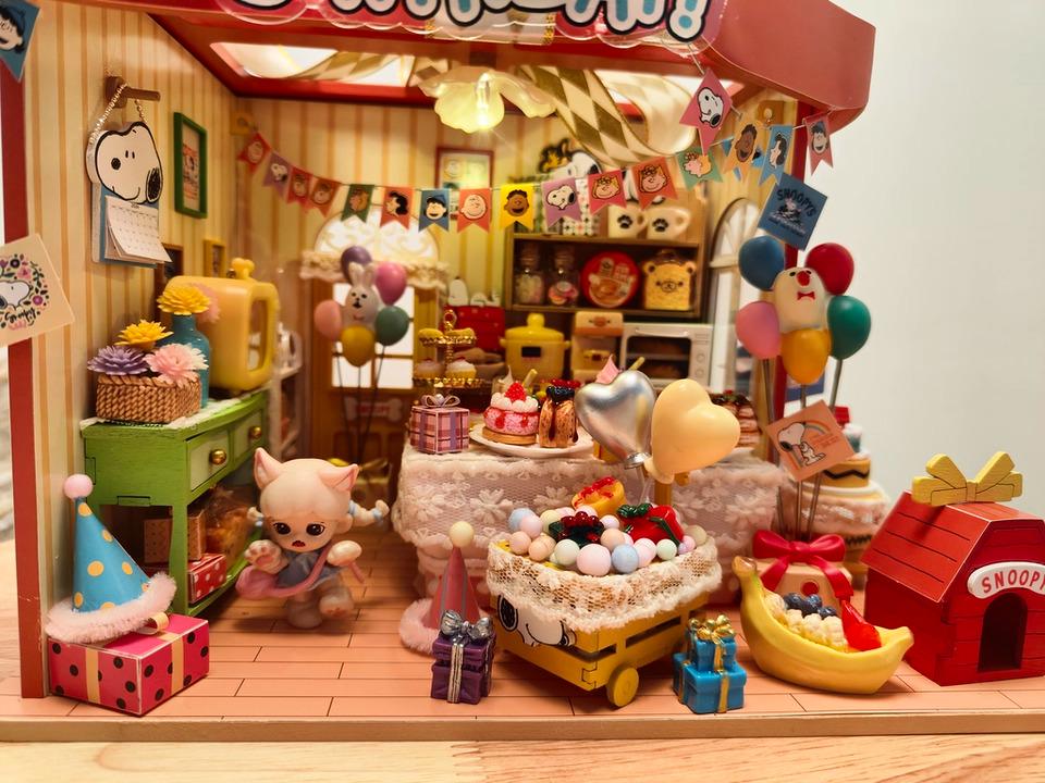 A miniature toy shop decorated for a birthday party, featuring various toys, decorations, and a cake.