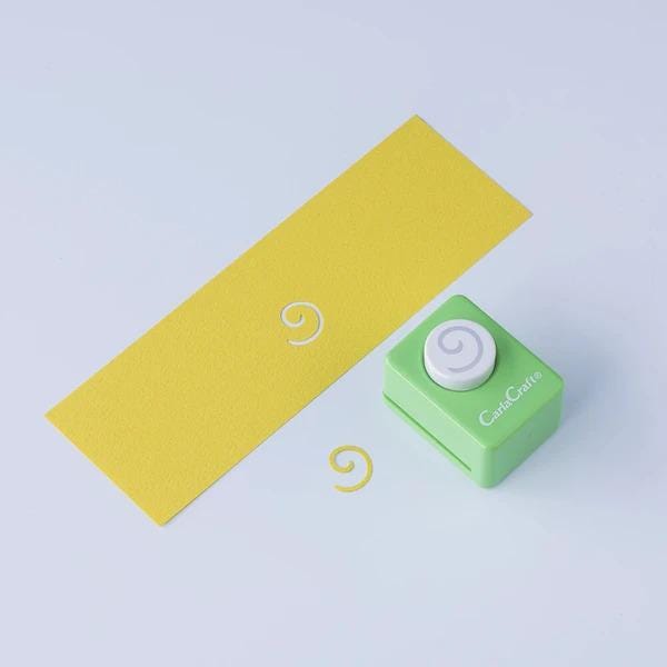 a yellow paper and a green paper cutter with a spiral design on it, along with a green paper cutter with a spiral design on it.