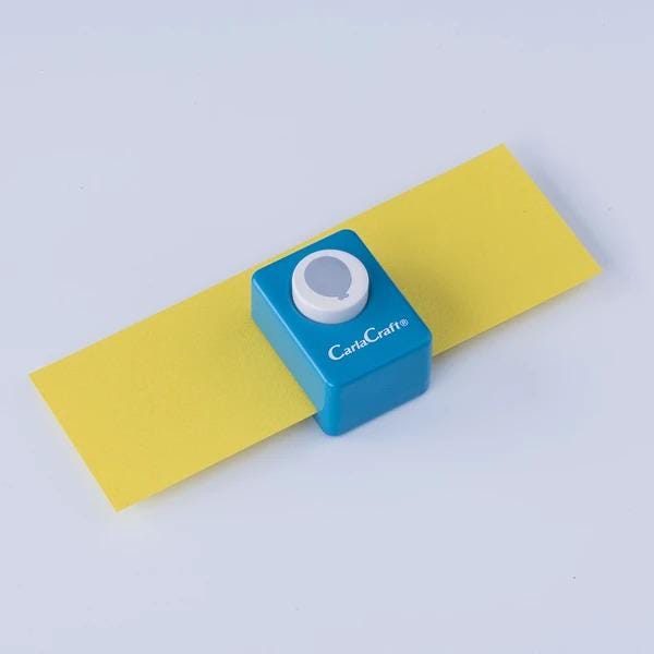 A blue and yellow paper cutter is placed on a yellow piece of paper against a white background.