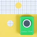A green hole puncher is placed on a yellow background with a grid pattern.