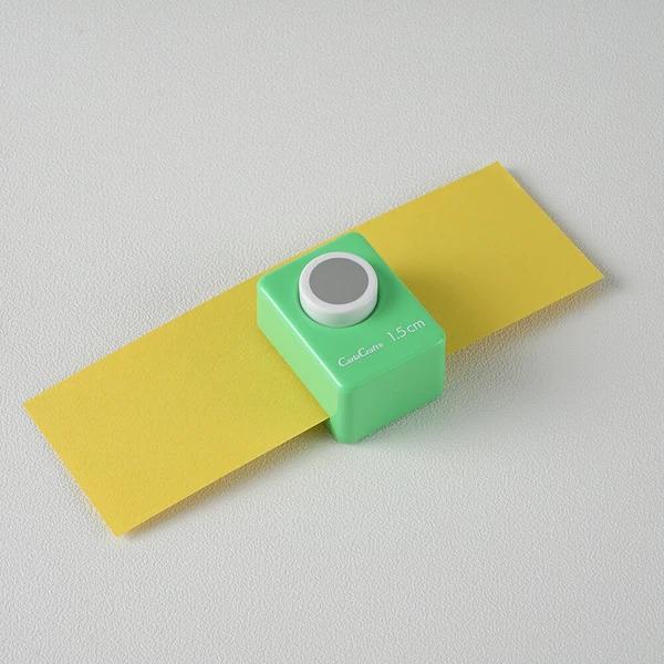 A green and yellow paper cutter is placed on a white surface.