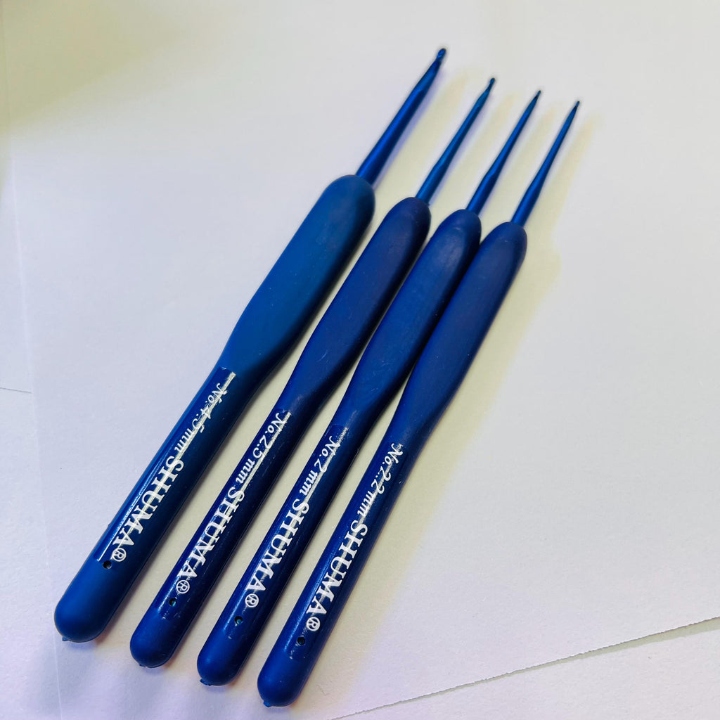 A group of four blue crochet hooks arranged on a white surface.
