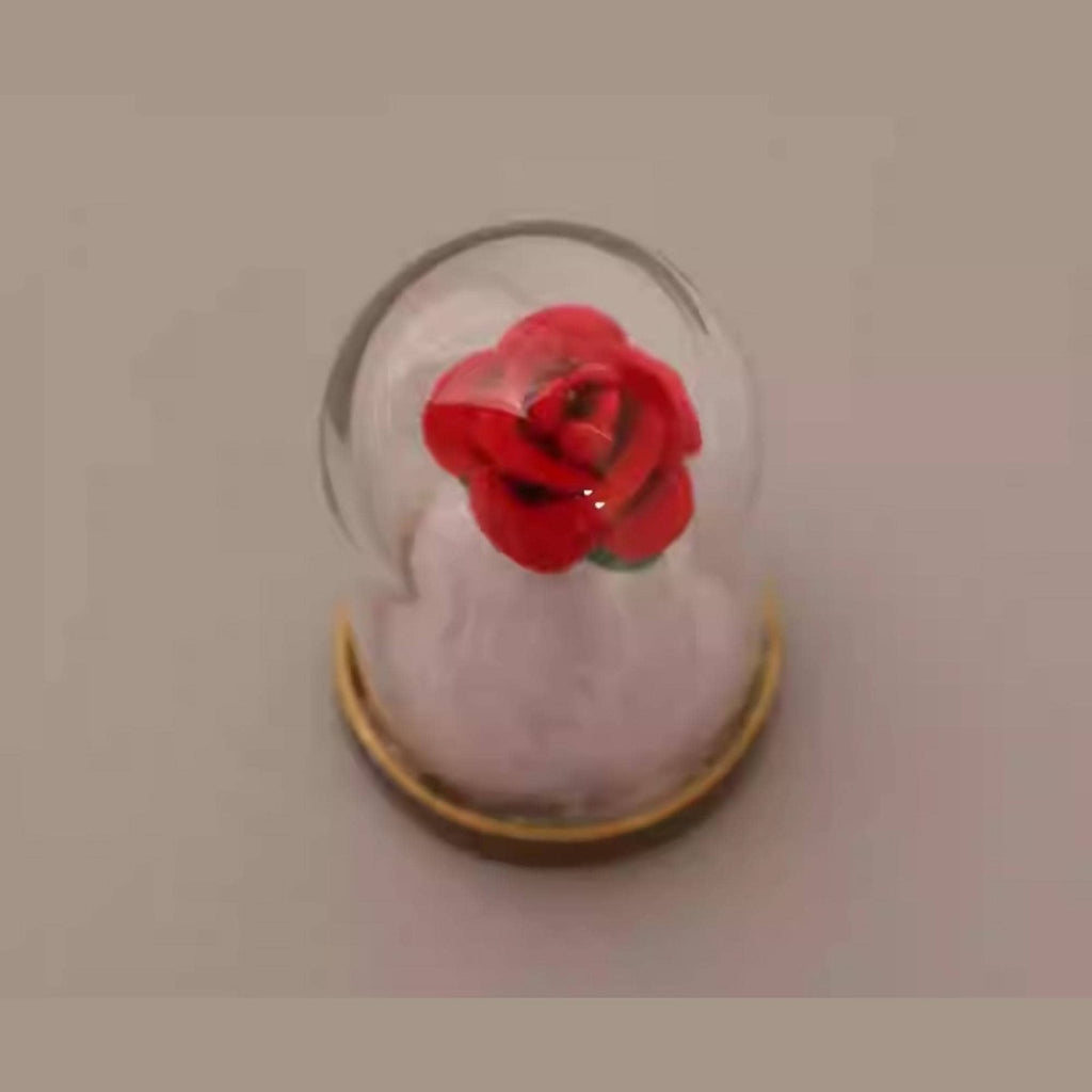 A red rose inside a glass dome, placed on a plain surface.