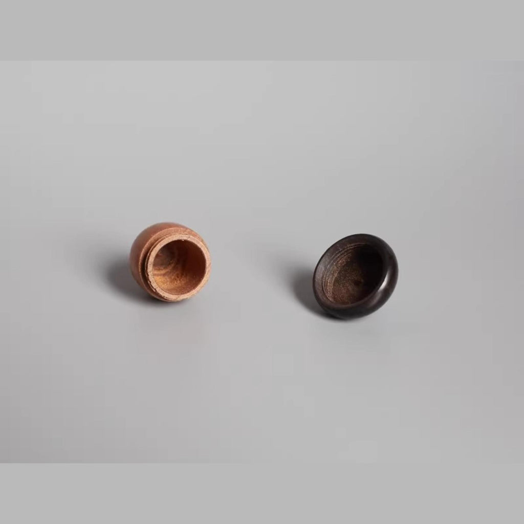 two wooden objects, one with a hole in it and the other without a hole, placed on a plain background.