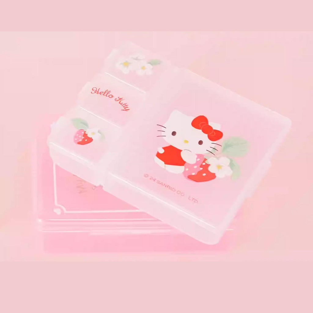 A pink container with a Hello Kitty design, featuring a strawberry and flower motif.