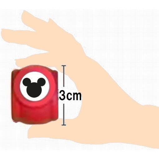 A hand holding a red object with a Mickey Mouse logo, with the object being approximately 3 centimeters in size.