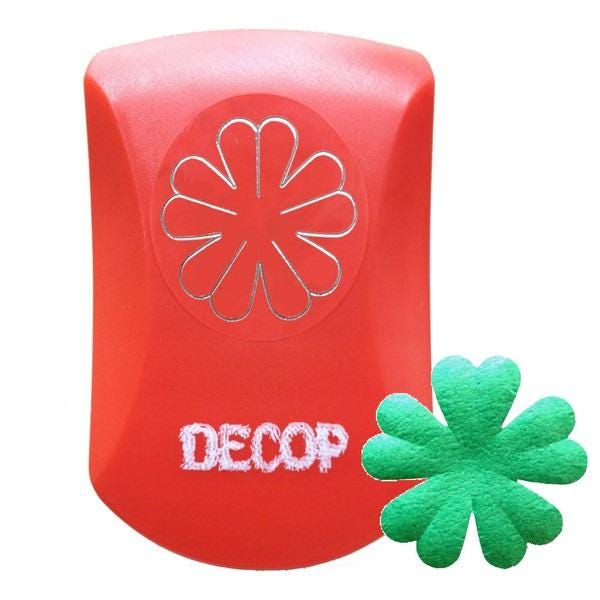 a red plastic object with a silver flower design on it, and a green fake four-leaf clover next to it.