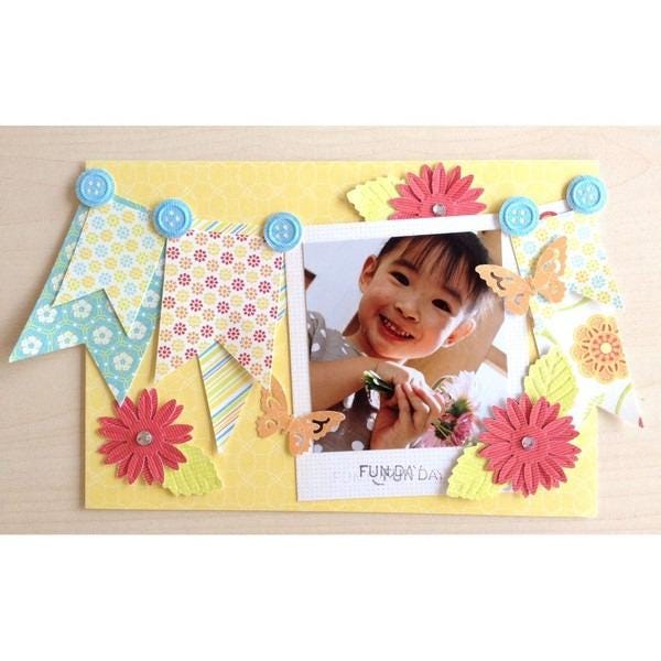 A handmade scrapbook page featuring a young child's photo, surrounded by colorful paper decorations, flowers, and butterflies.