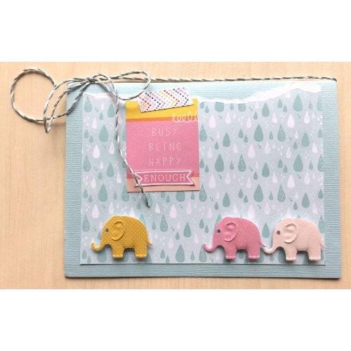 A handmade greeting card featuring three elephant-shaped cutouts, with a pink and blue background and the text "Busy being happy enough" written on the card.