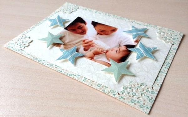A handmade greeting card featuring a family portrait of two adults and a child, surrounded by decorative star-shaped embellishments.
