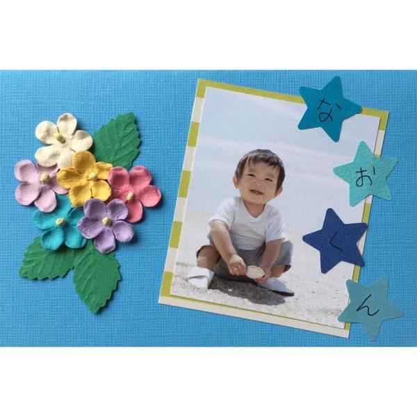 A collage of a young boy sitting on the ground, surrounded by colorful flowers and star-shaped decorations, with a photograph of the boy in the center.
