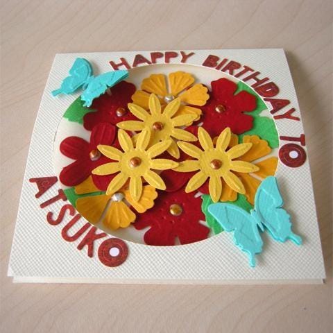 A handmade birthday card featuring a colorful arrangement of flowers and butterflies.