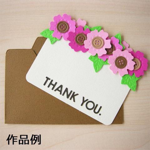 A white card with the text "THANK YOU" written on it, surrounded by colorful plastic flowers.
