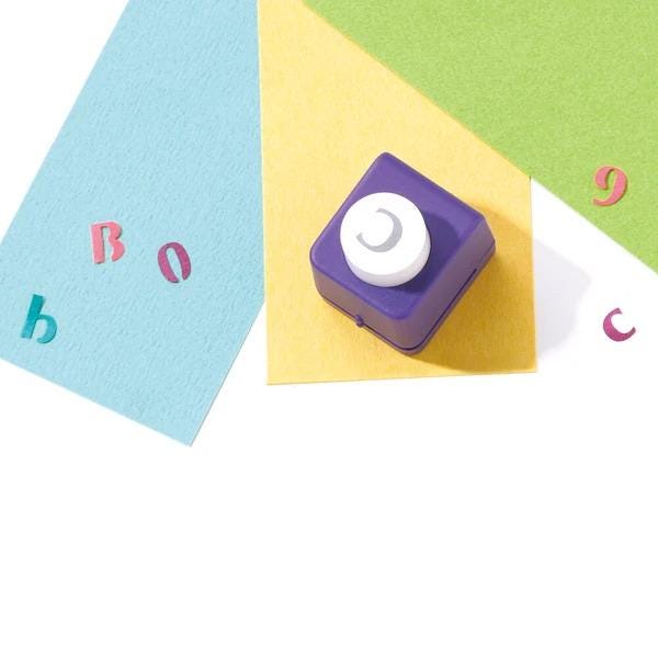 a purple hole puncher on a yellow surface, surrounded by colorful papers and cut-out shapes.