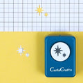 A blue hole puncher with star-shaped cutouts is placed on a yellow background with a grid pattern.