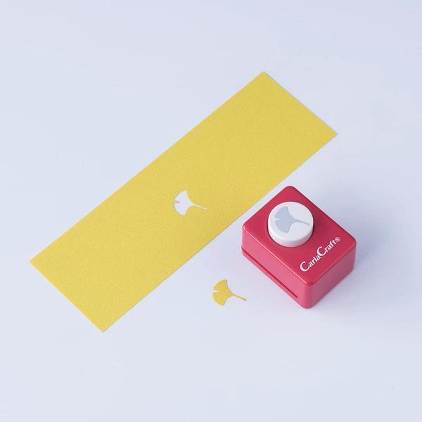 a yellow paper and a red paper punch with a white gash, both placed on a white background.