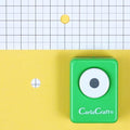 A green hole puncher with a white eye design is placed on a yellow background with a grid pattern.