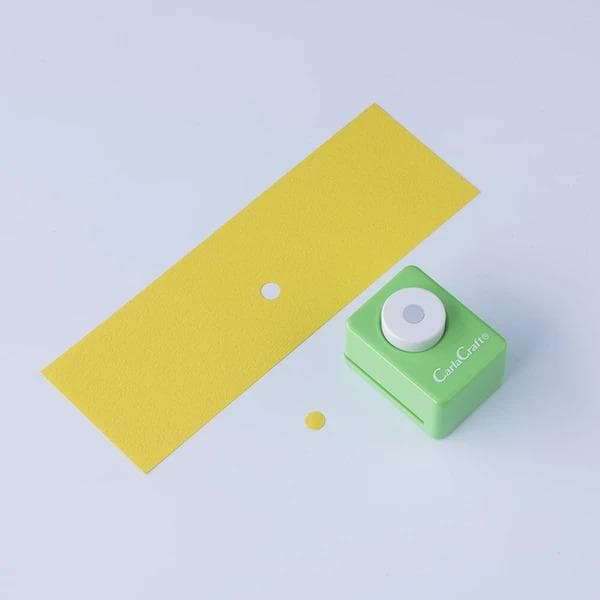 a green paper cutter with a yellow paper strip on a white background.