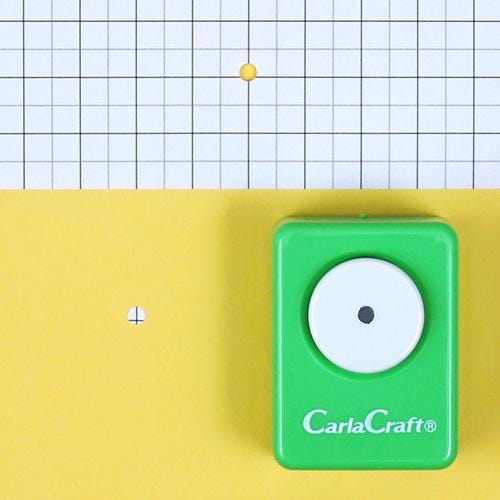 a green hole puncher on a yellow background, with a grid pattern visible in the background.