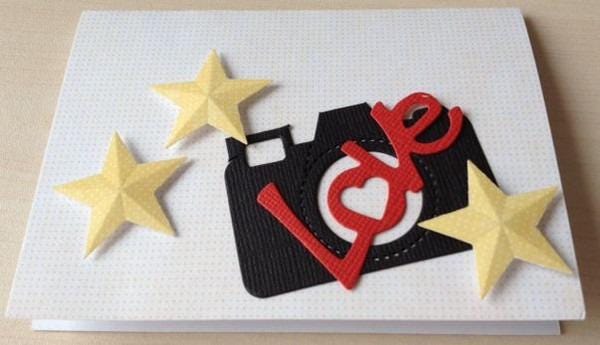 A handmade card with a black camera cutout and three yellow star cutouts.