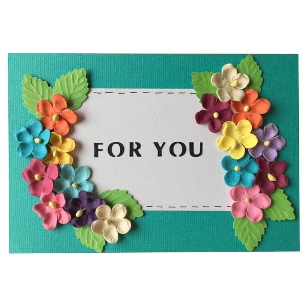 A handmade greeting card with a white frame and colorful flowers surrounding it. The text "FOR YOU" is displayed in the center of the frame.