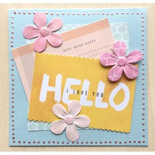 A handmade greeting card with a yellow background, featuring the word "HELLO" in bold white letters, surrounded by pink and white paper flowers.