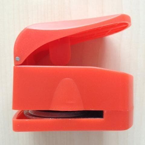 a red plastic container with an open lid, placed on a wooden surface.