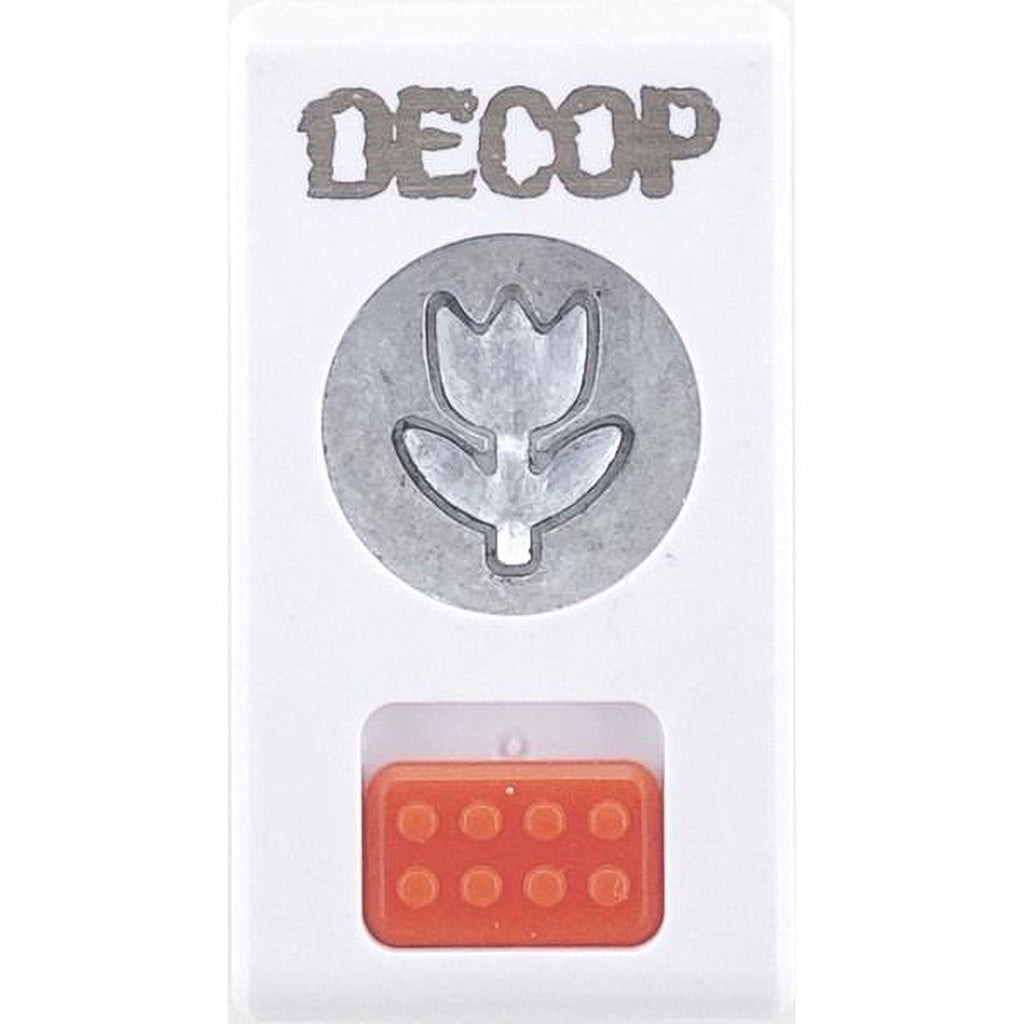 a white rectangular object with a silver flower-shaped cutout in the center, and an orange plastic block with a hole in the bottom.