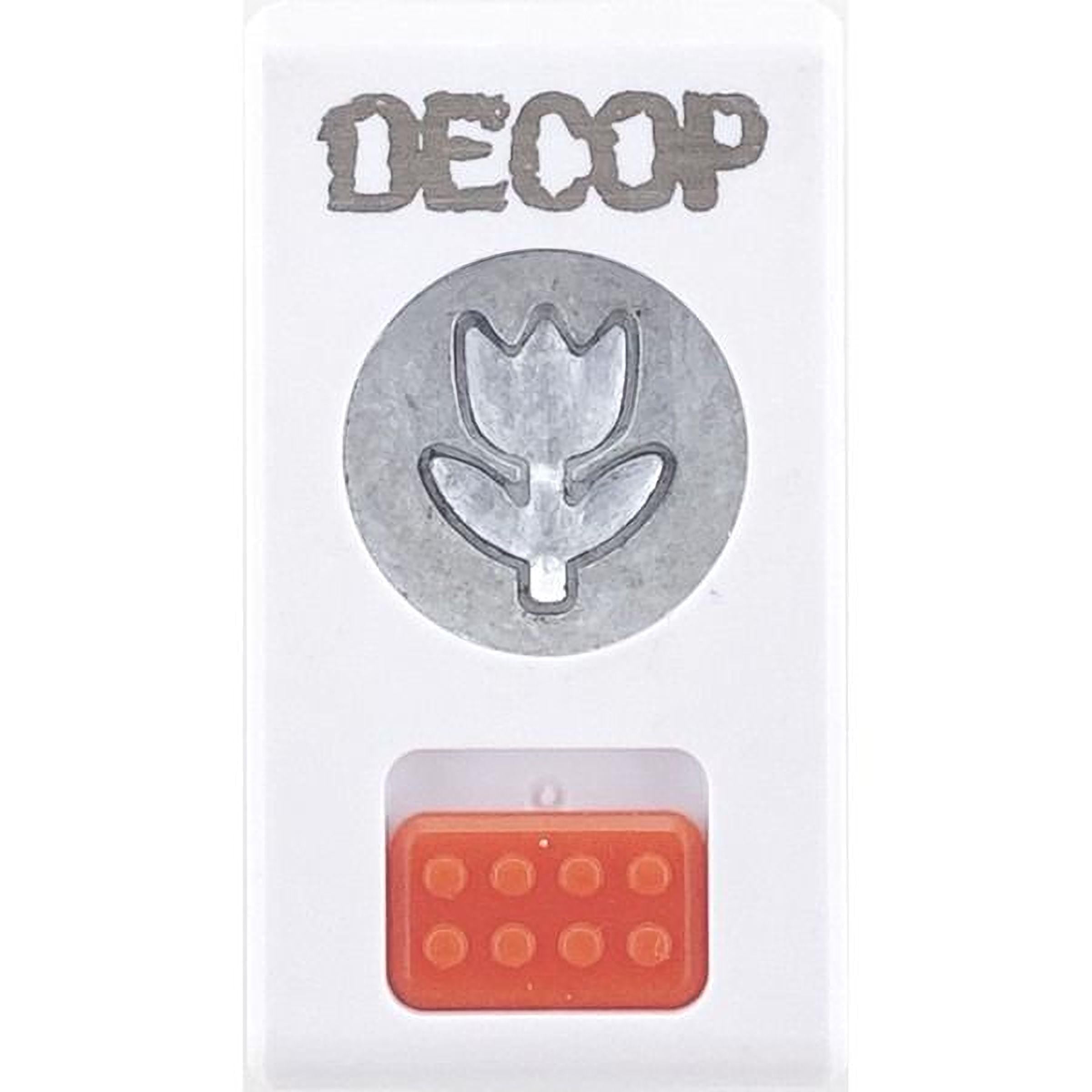 a white rectangular object with a silver flower-shaped cutout in the center, and an orange plastic block with a hole in the bottom.